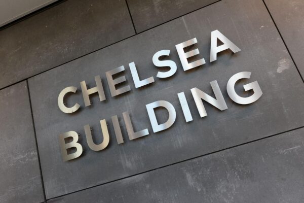 Metalen letters met de tekst "Chelsea Building" op een donkere gevel aan de Laan van Zuid Hoorn.